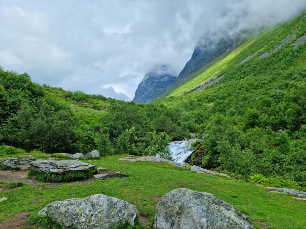 The trail reveals Storsæterfossen tucked into the green mountainside.